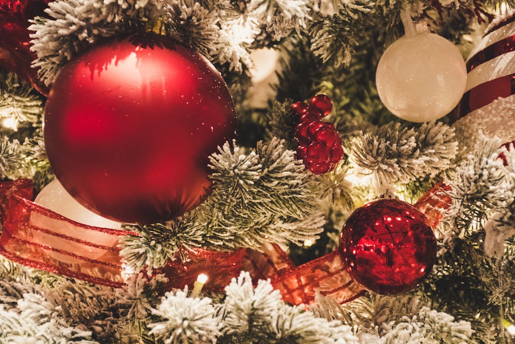 Close-up of festive Christmas tree decorated with red and white ornaments and snow-covered branches.